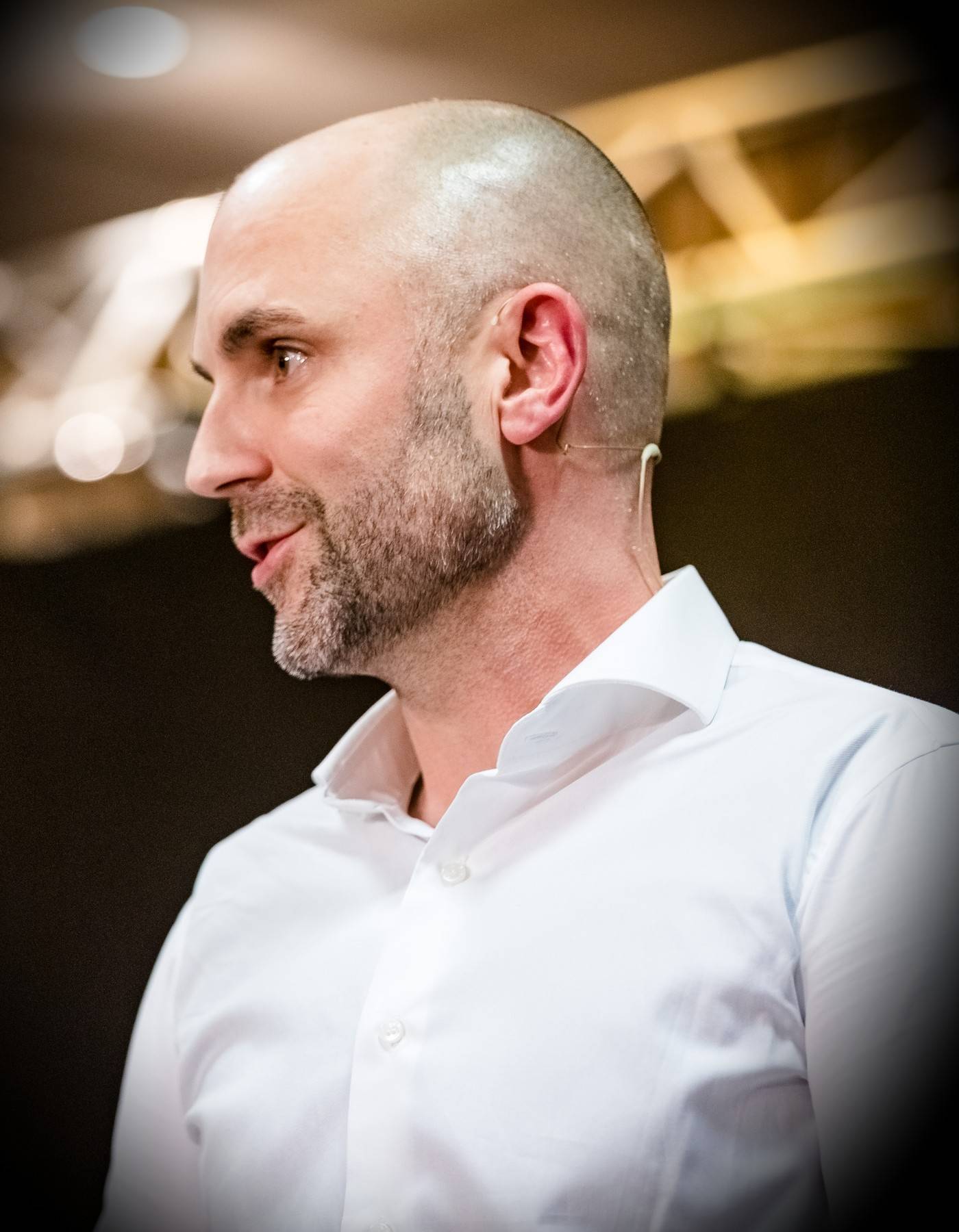 Dr. med. Niels Freitag im Profil auf der Bühne, mit Headset-Mikrofon